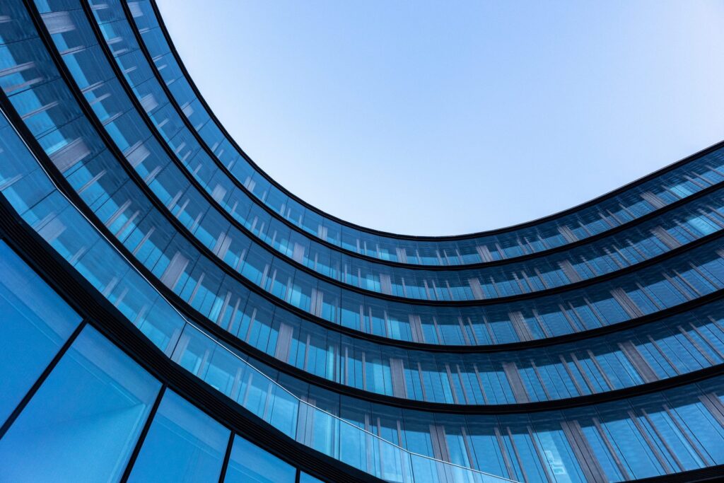 Gebogenes Glasgebäude mit blauem Himmel im Hintergrund
